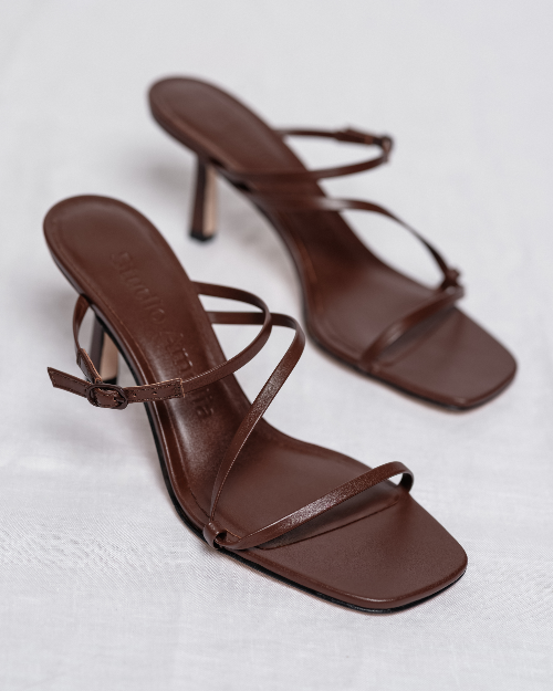 Pair of brown high-heeled sandals on a light gray background