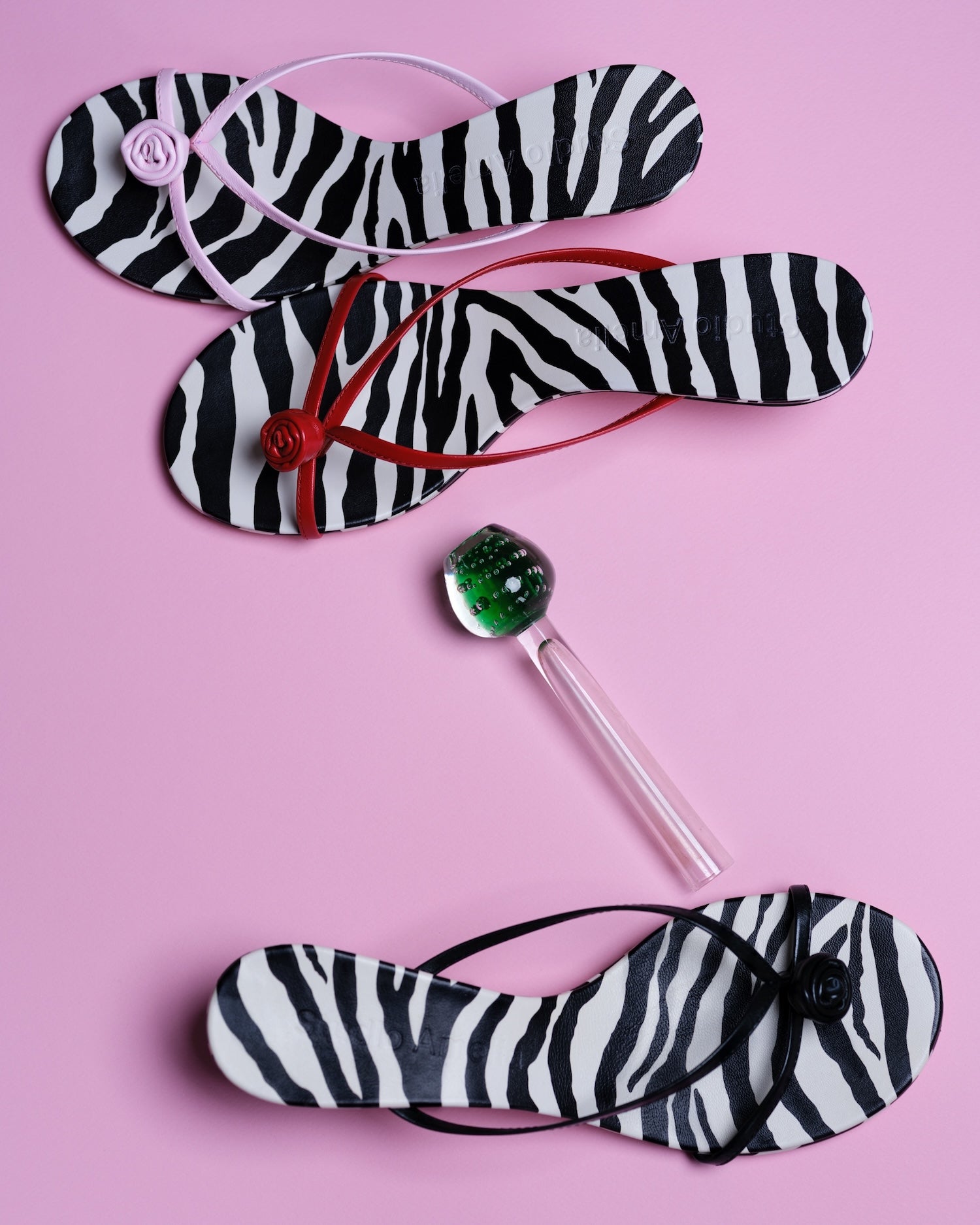 Zebra-striped flip-flops with a lollipop on a pink background
