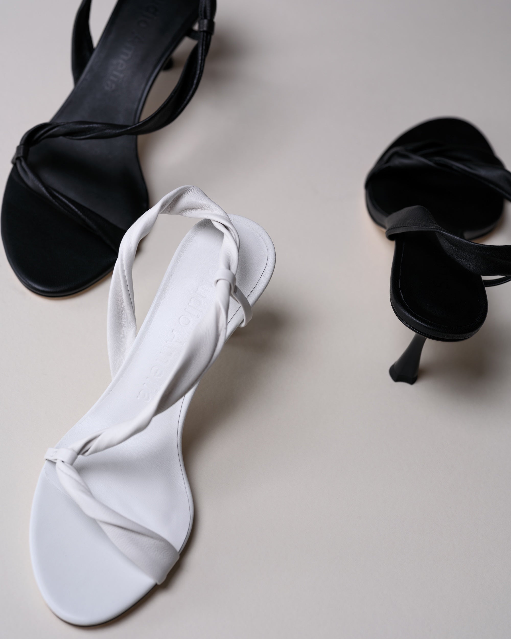 White sandal with black high heels on a light gray background