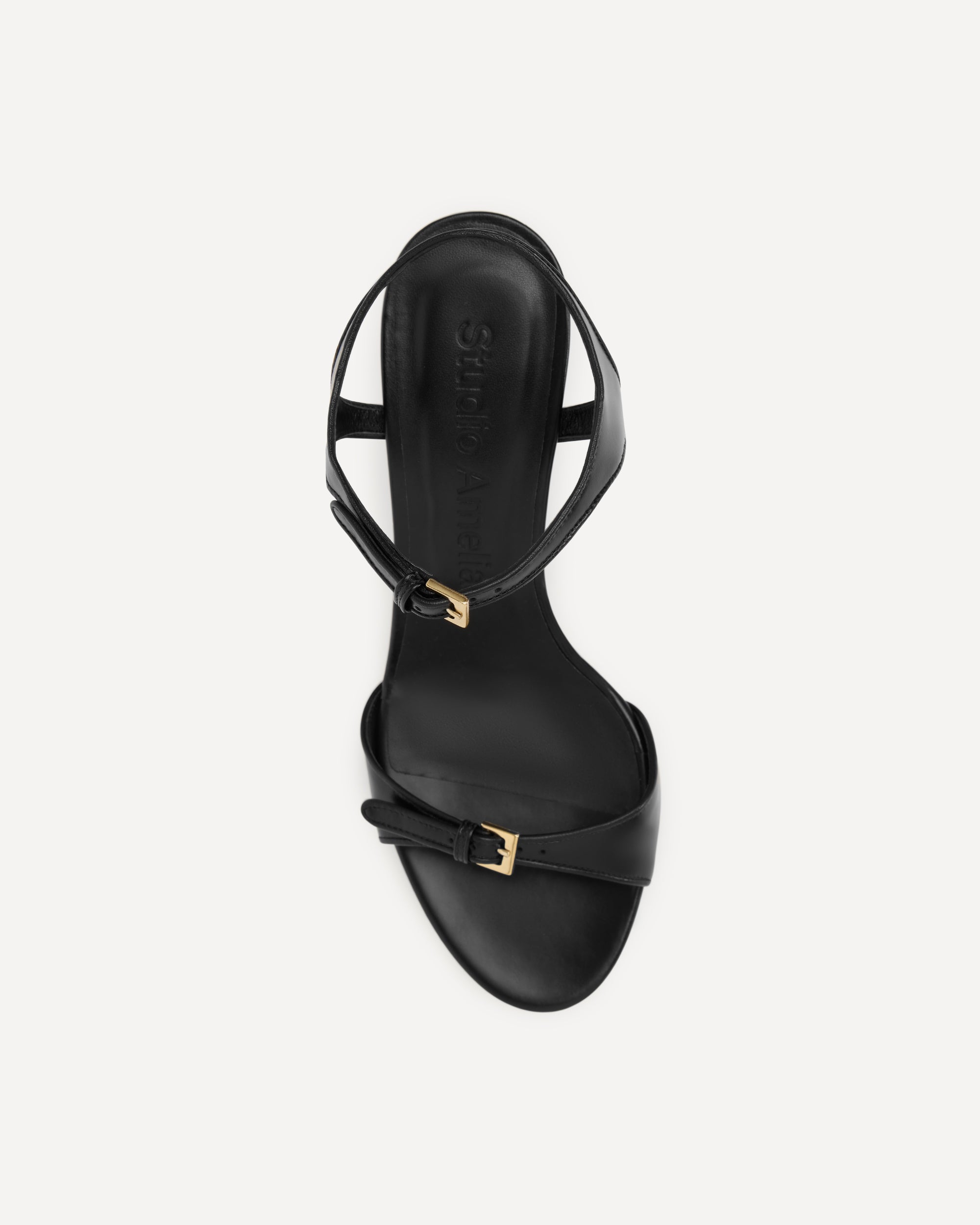 Black sandal with gold buckle on a white background