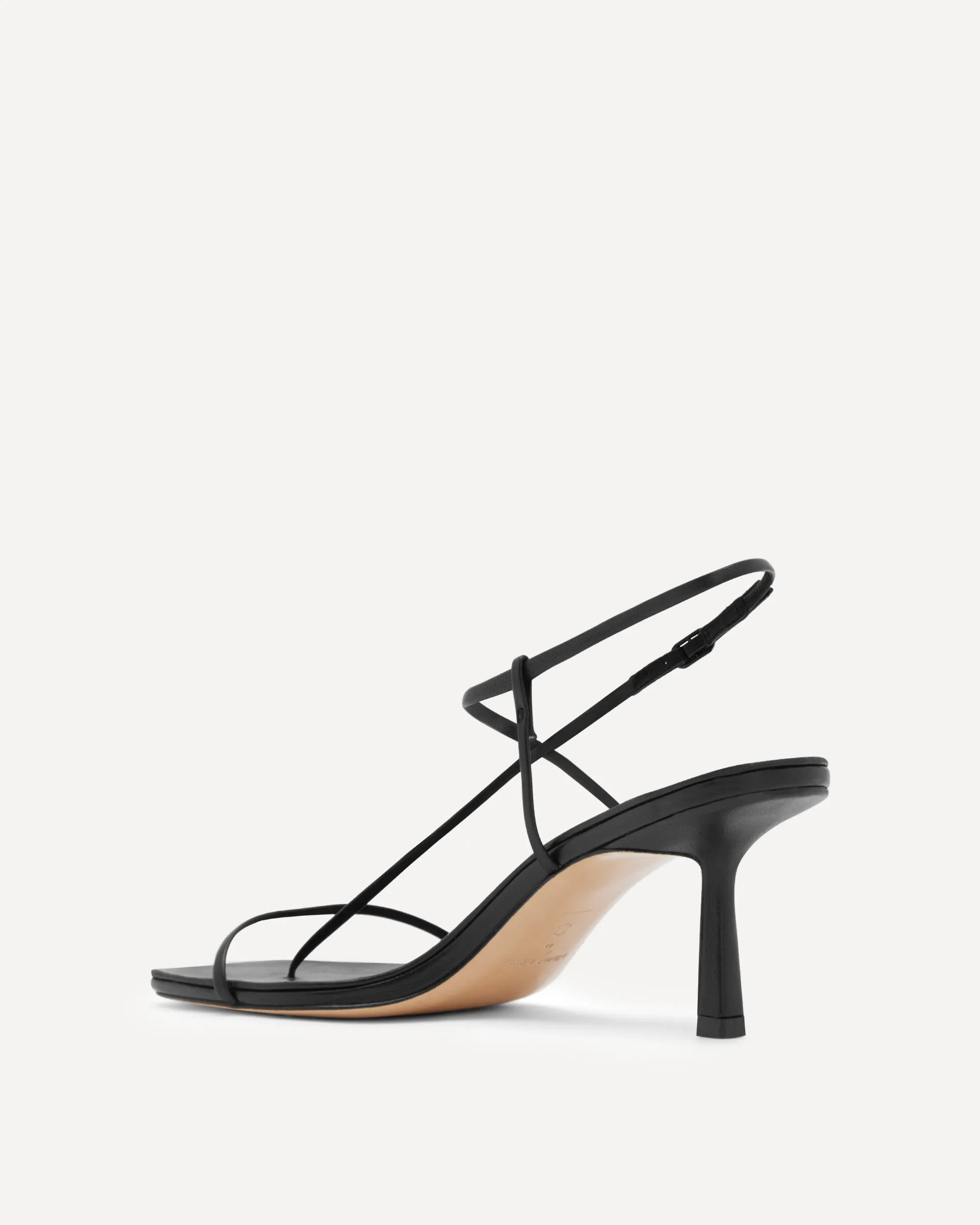 A single black strappy high-heeled sandal with a slim heel and ankle strap, shown from a side profile on a light gray background.