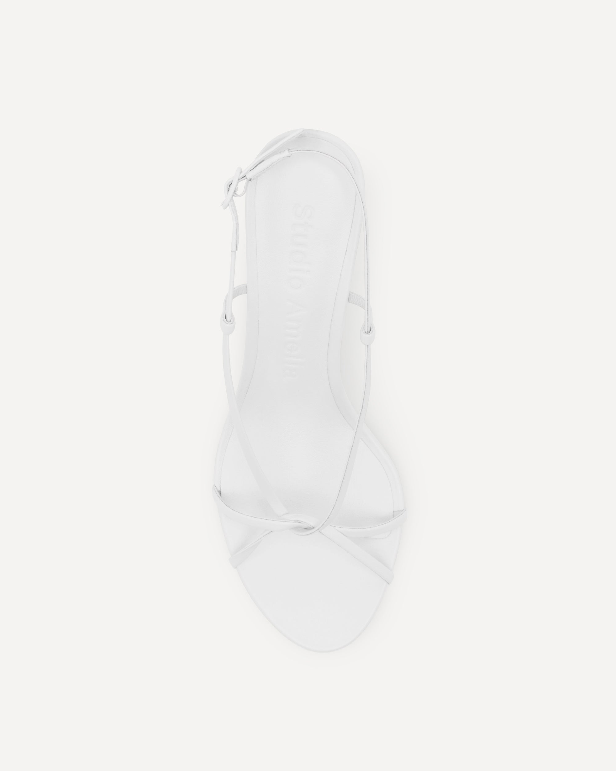 Top view of a white strappy high heel sandal on a white background