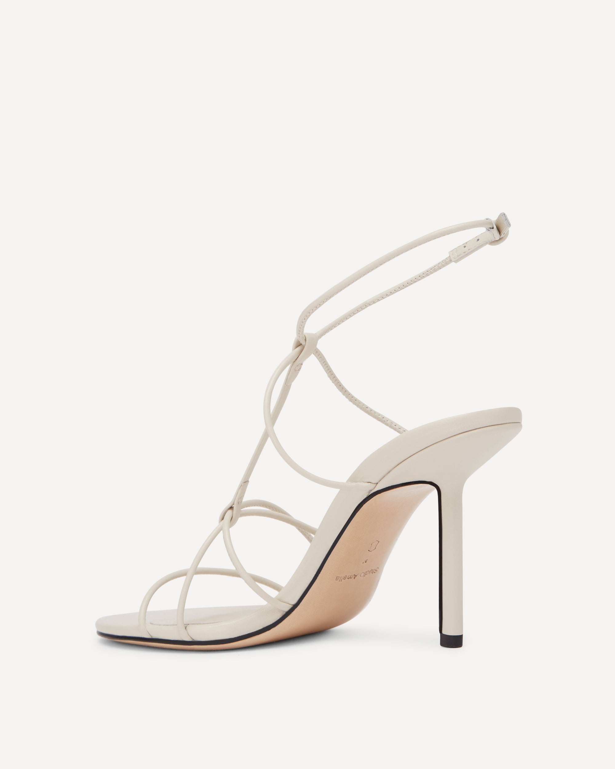 A white high heeled shoe with thin straps