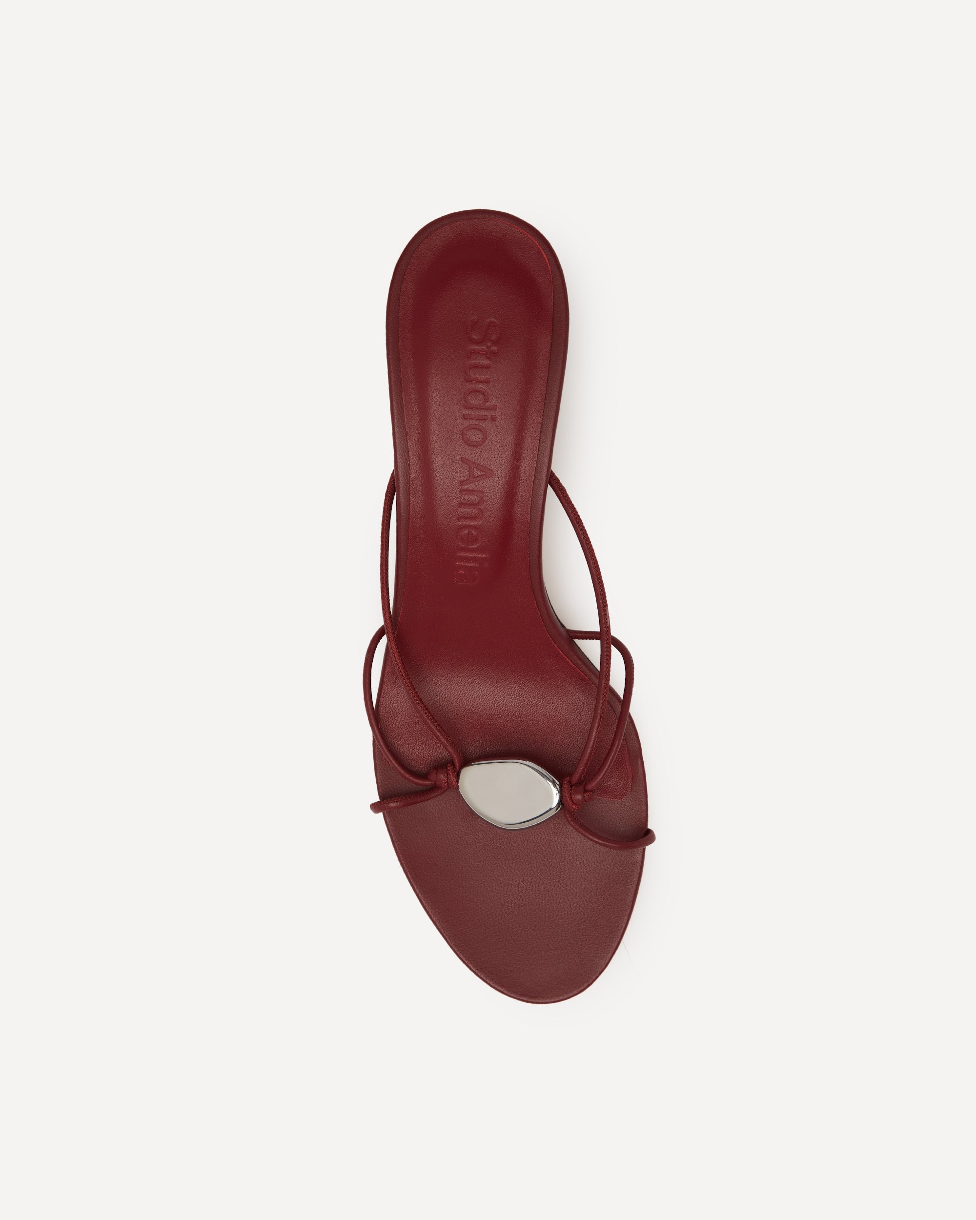 A red sandal with straps and a silver pebble