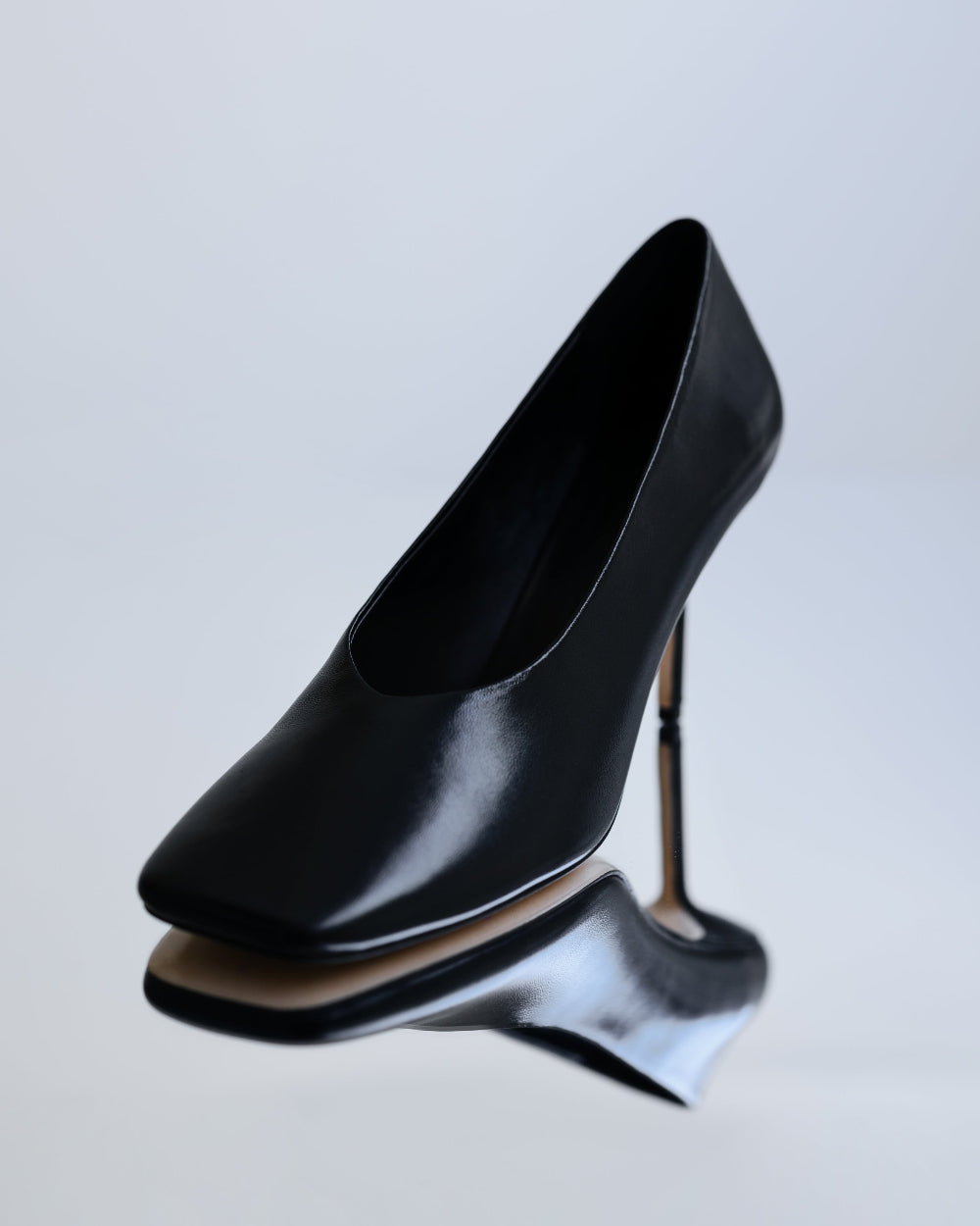 Black high-heeled shoe on a light gray background