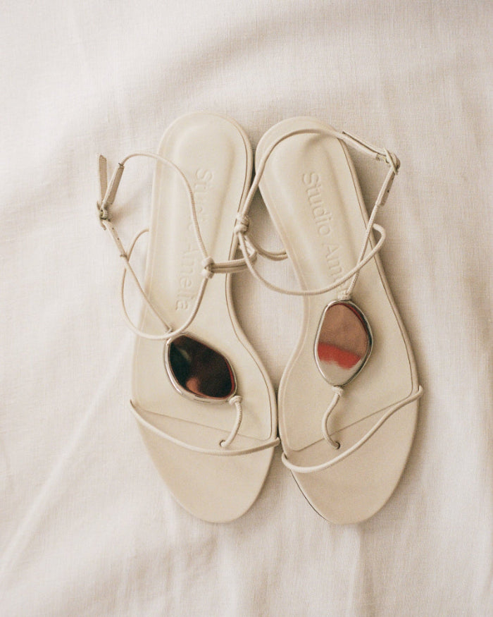Pair of beige sandals with thin straps on a light background