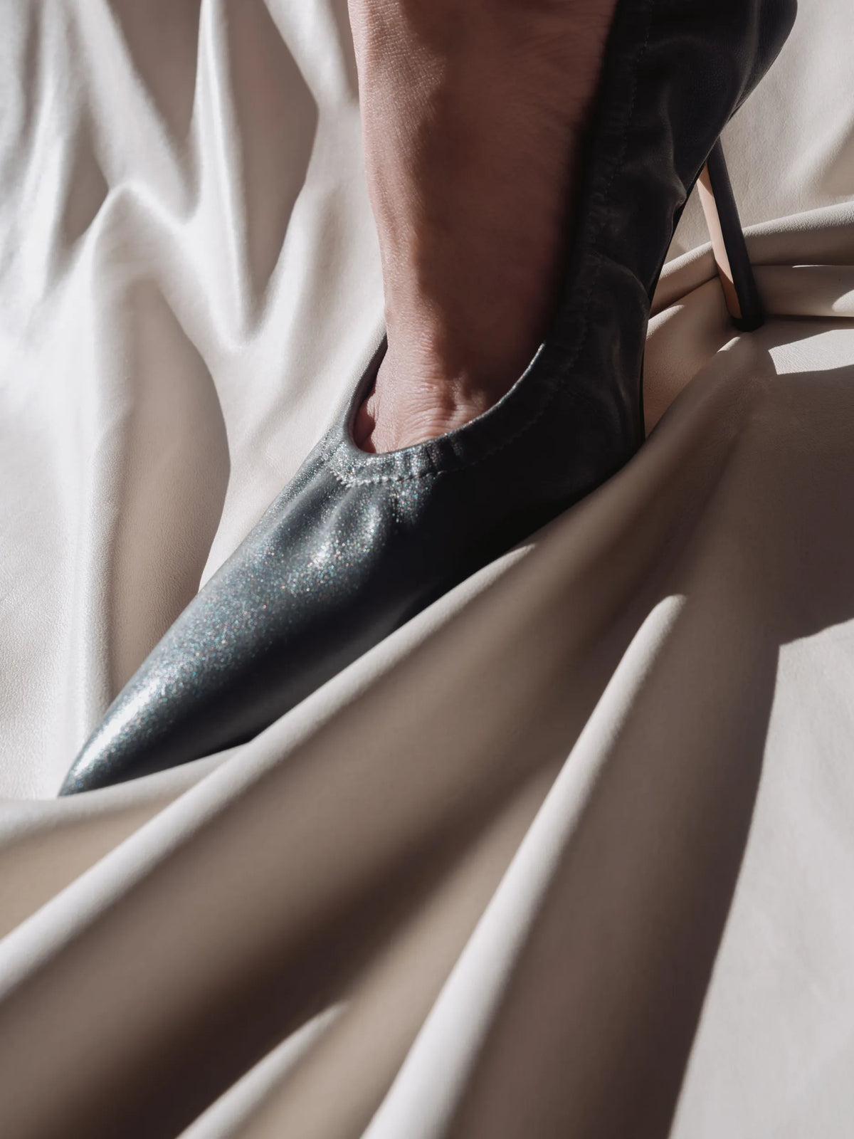 A woman wearing a grey pointed leather pump with a high heel