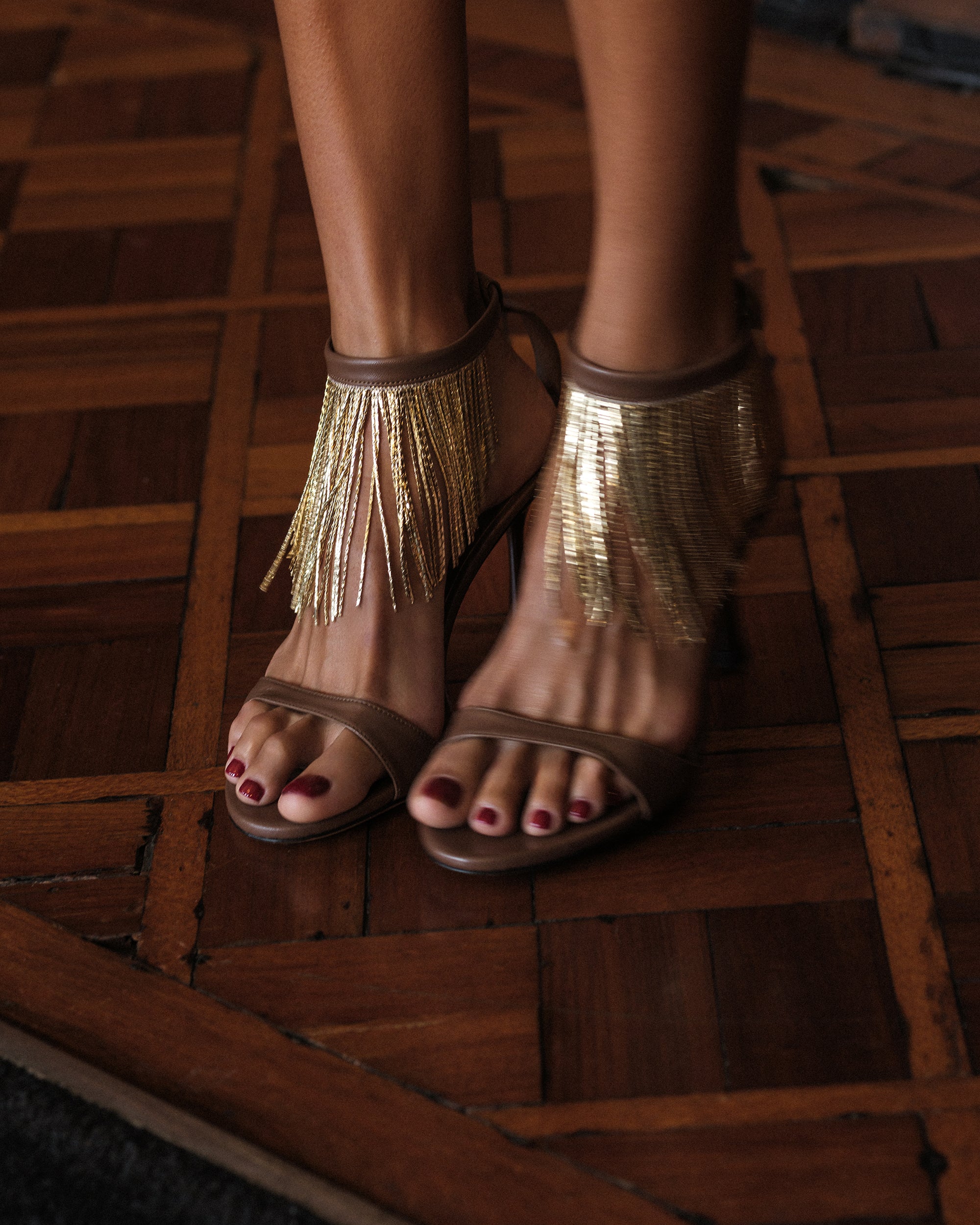 A pair of brown high heels with gold chains