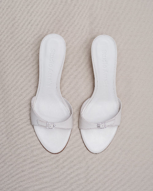 Pair of white sandals on a beige surface