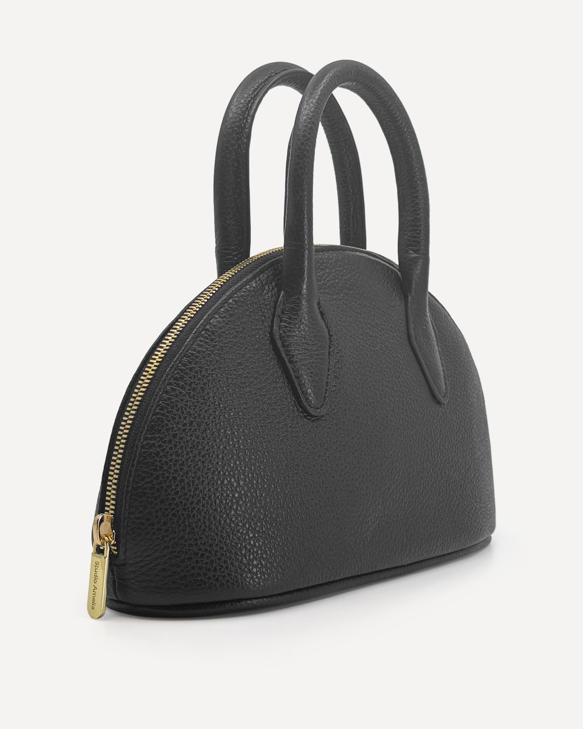 Black handbag with gold zipper on a white background