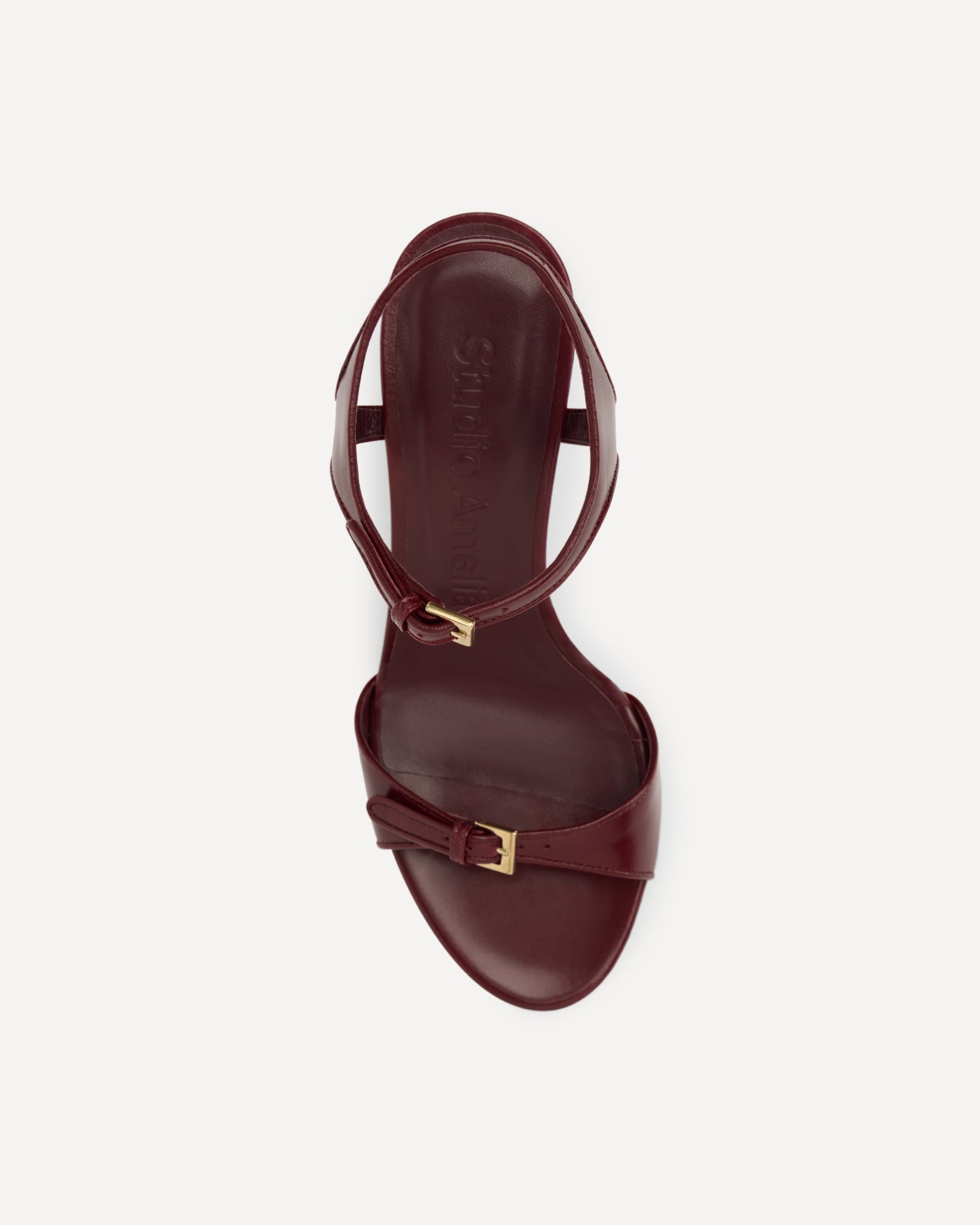 Maroon high-heeled sandal with gold straps on a white background