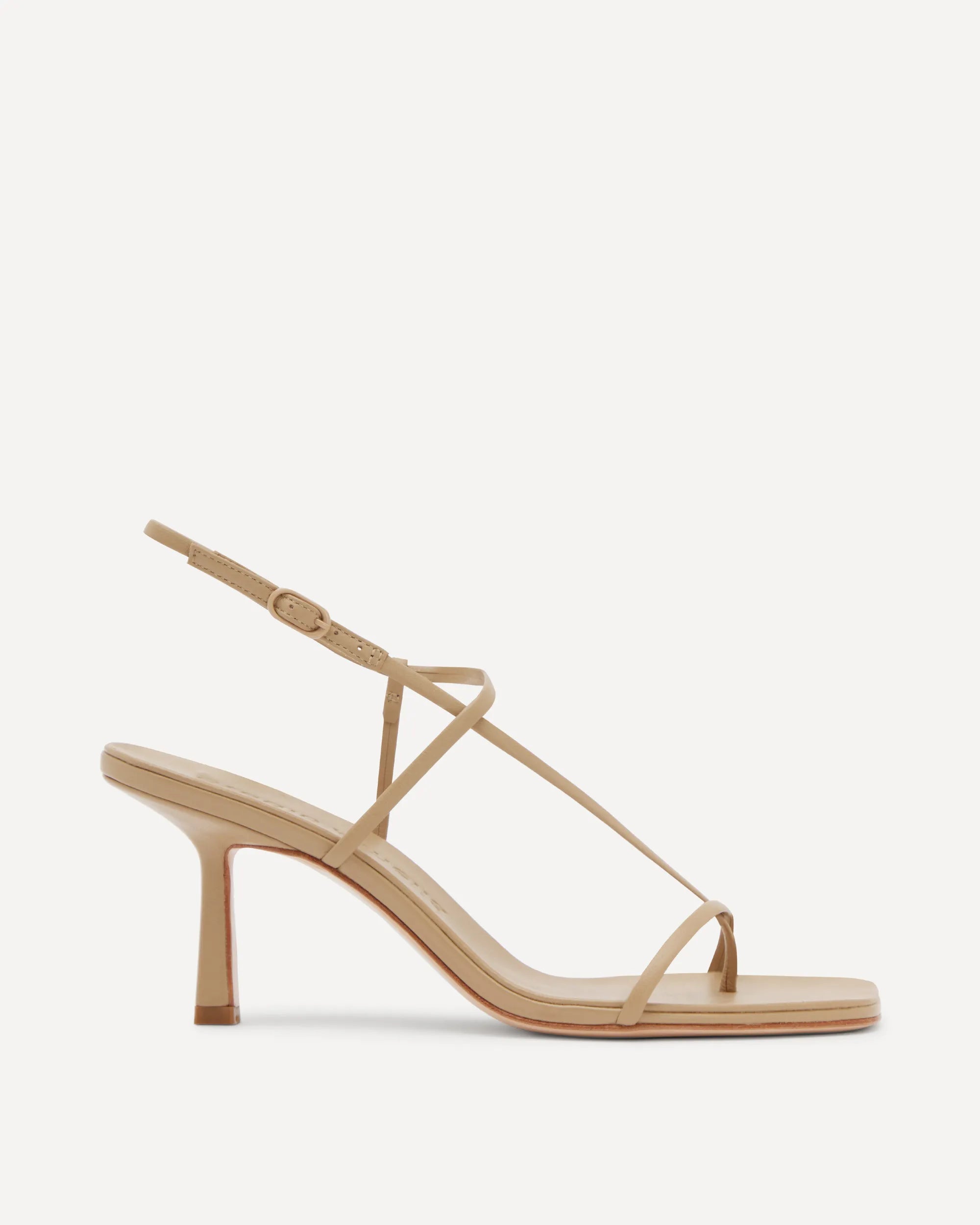 A single beige strappy sandal with a mid-height stiletto heel, shown in a side profile against a clean, off-white background.