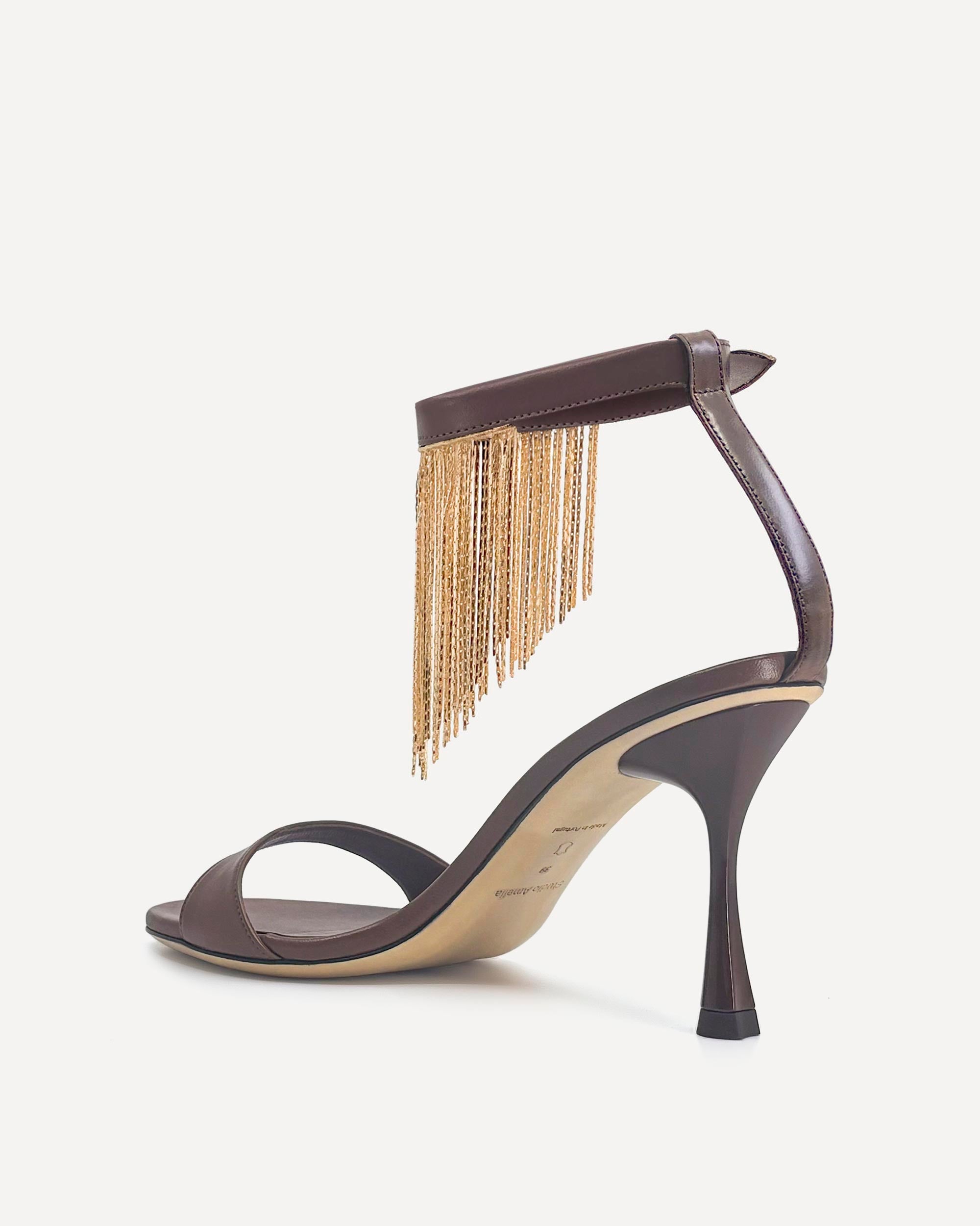 High-heeled sandal with gold fringe on a white background