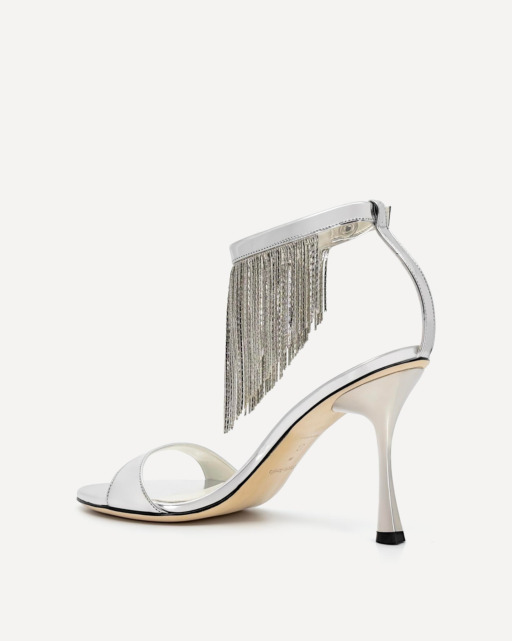 Silver high-heeled sandal with fringe detail on a white background