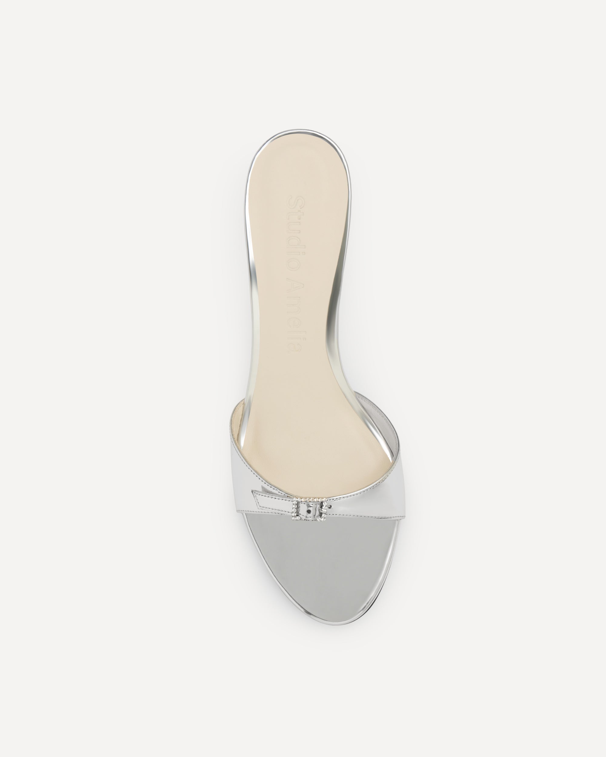 A silver sandal with a buckle on a white background