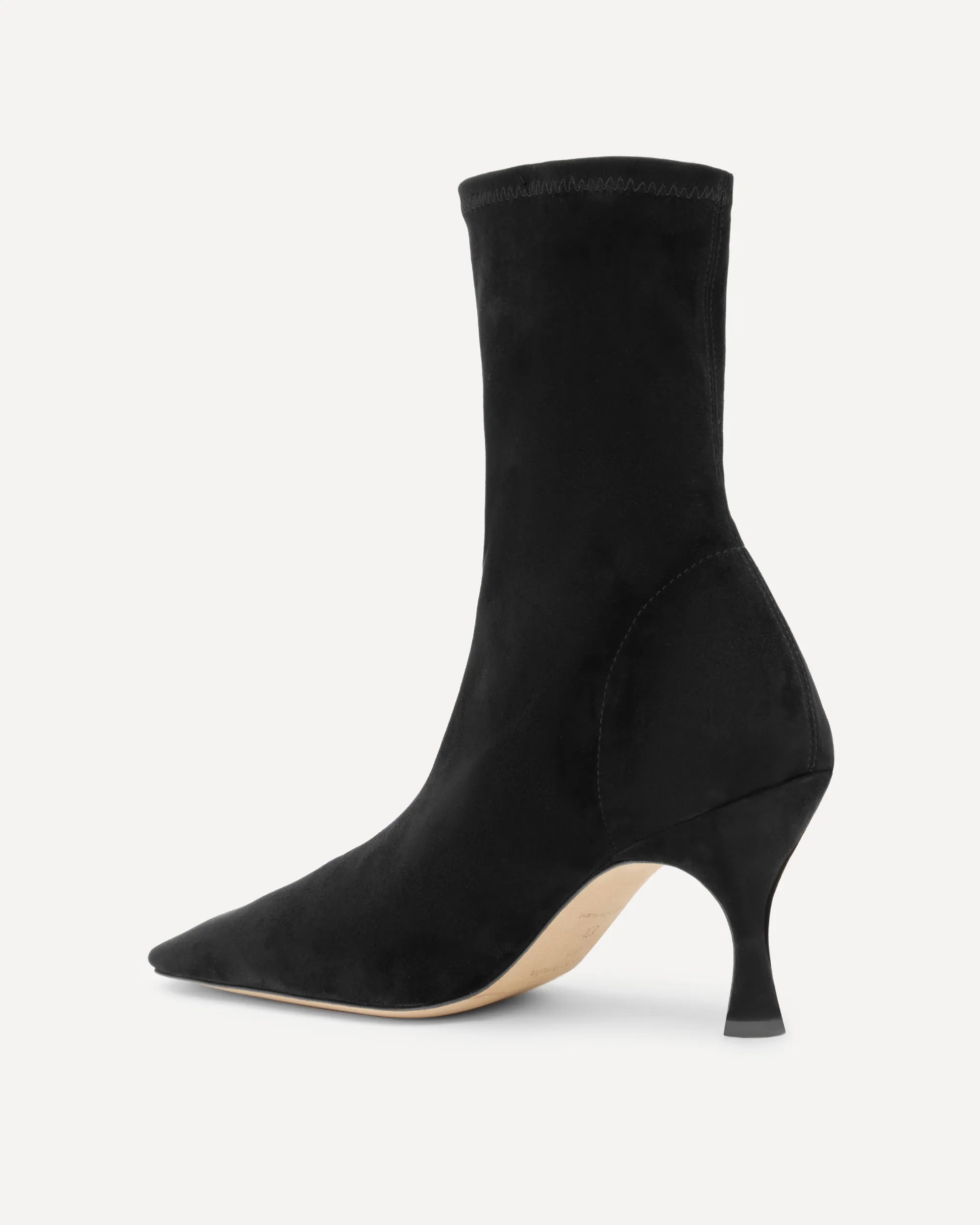 A black suede sock boot with a pointed toe and a slim kitten heel, shown from a side profile on a light gray background.