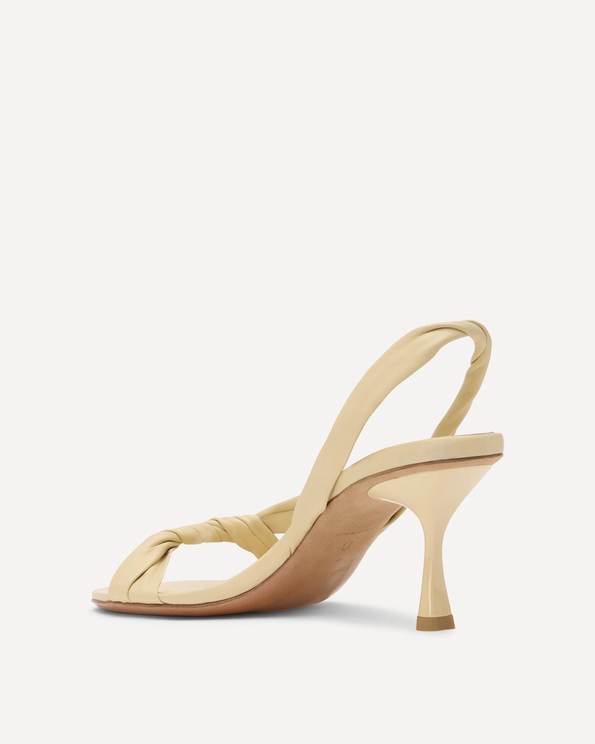 A single light beige slingback sandal with a twisted front strap and a mid-height kitten heel, shown from a side profile on a clean white background.