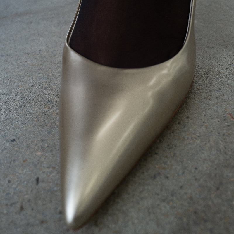 Gold high-heeled shoe on a gray concrete surface