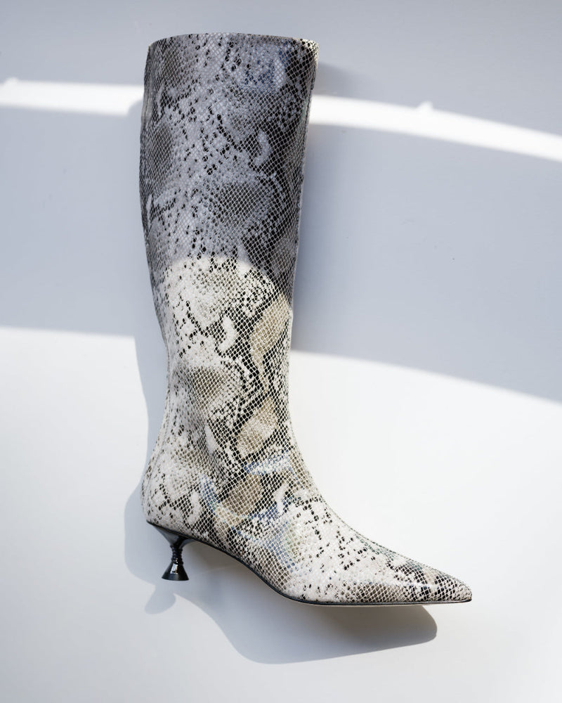 Snakeskin-patterned knee-high boot on a light background