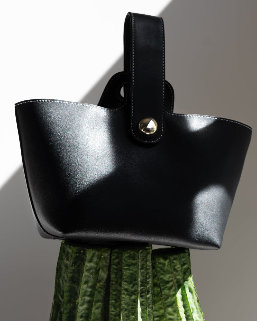 Black handbag with a gold clasp on a white background