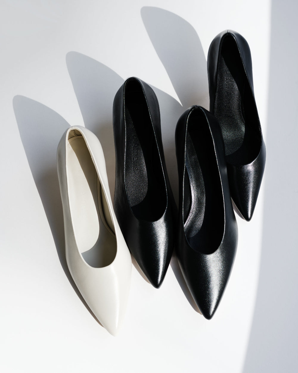 Black and white pointed-toe heels on a white background