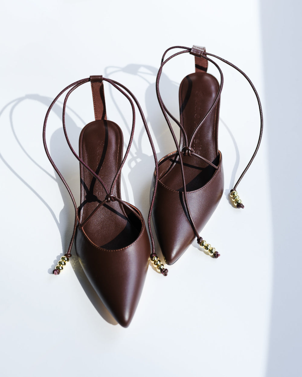 Pair of brown strappy high heels on a white background