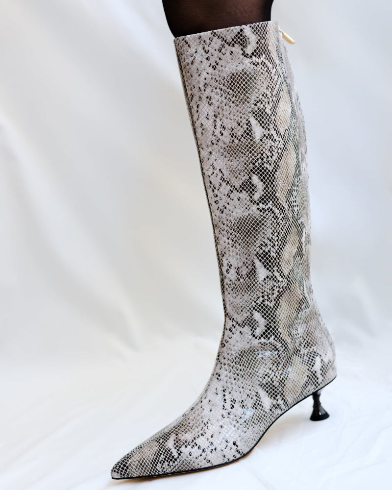 Snakeskin-patterned knee-high boot on a white background