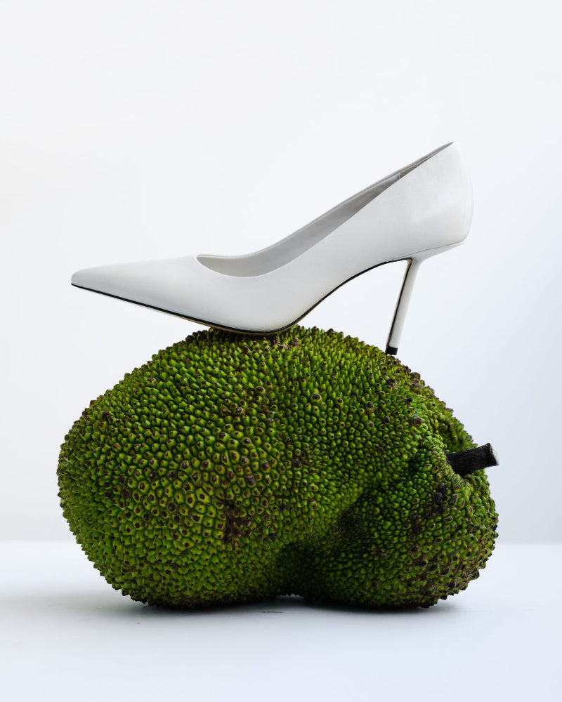 White high heels made from leather sitting on a fruit