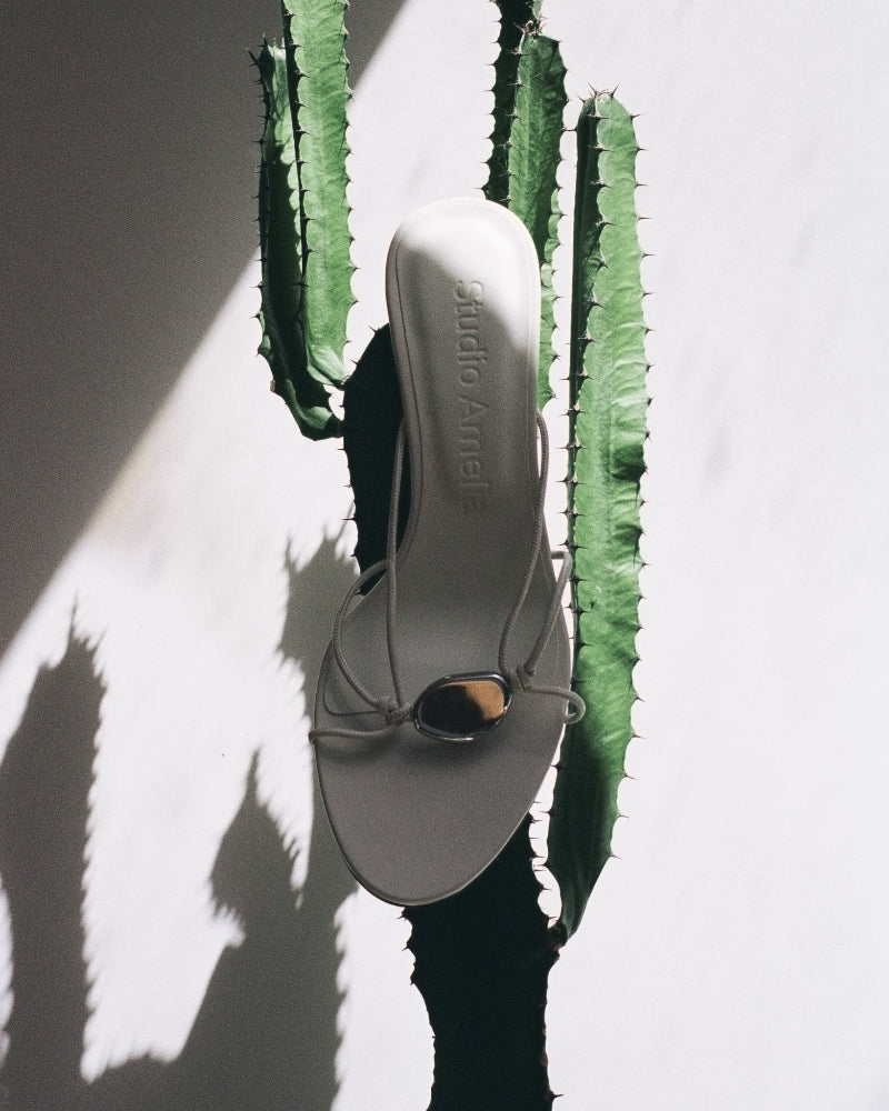 A white sandal with a silver pebble by Studio Amelia