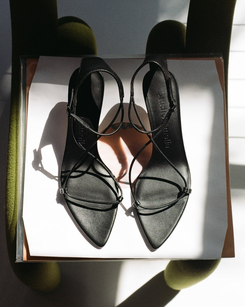 Black strappy high heels on a white box 