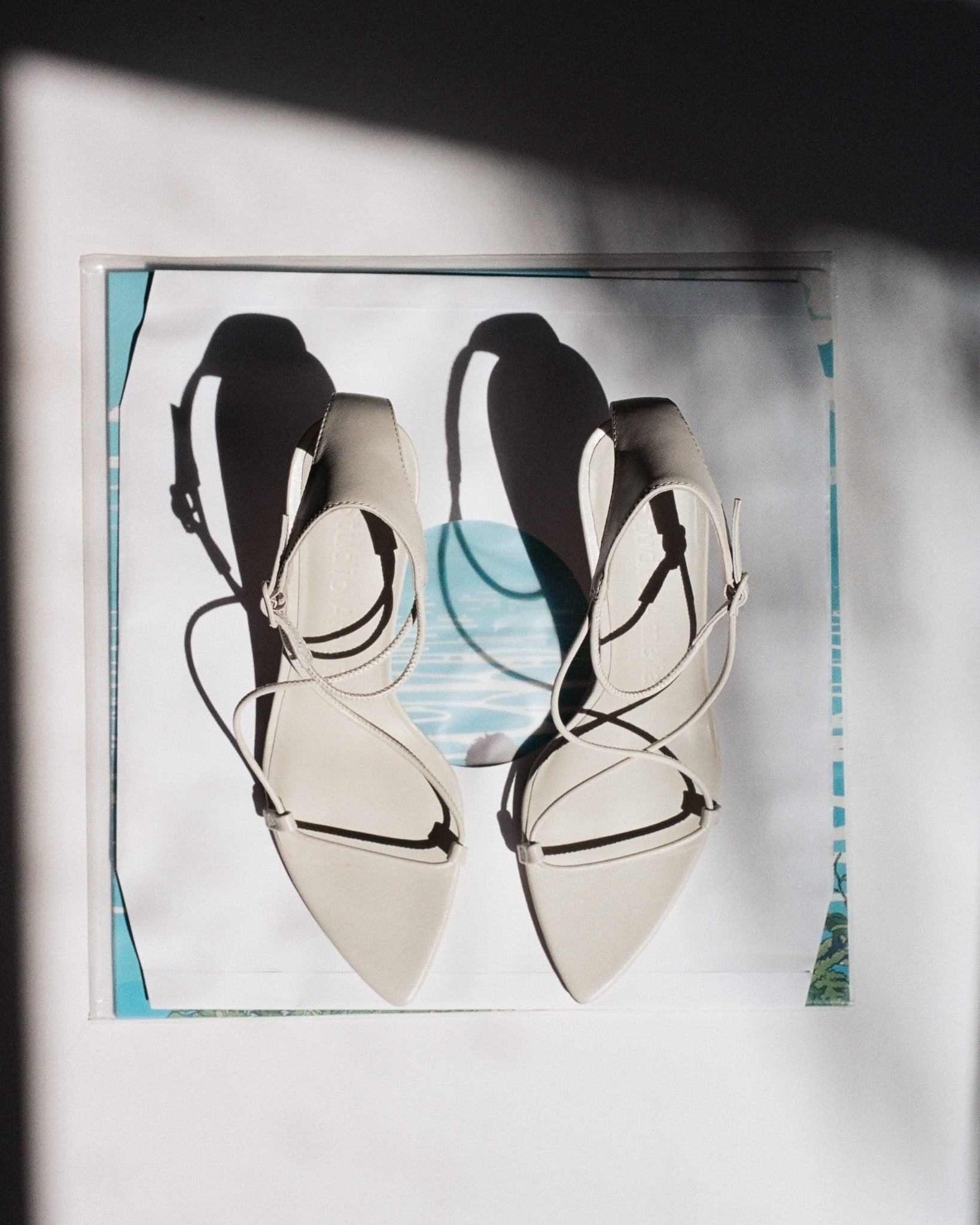 Pair of high-heeled shoes with thin straps on a white background