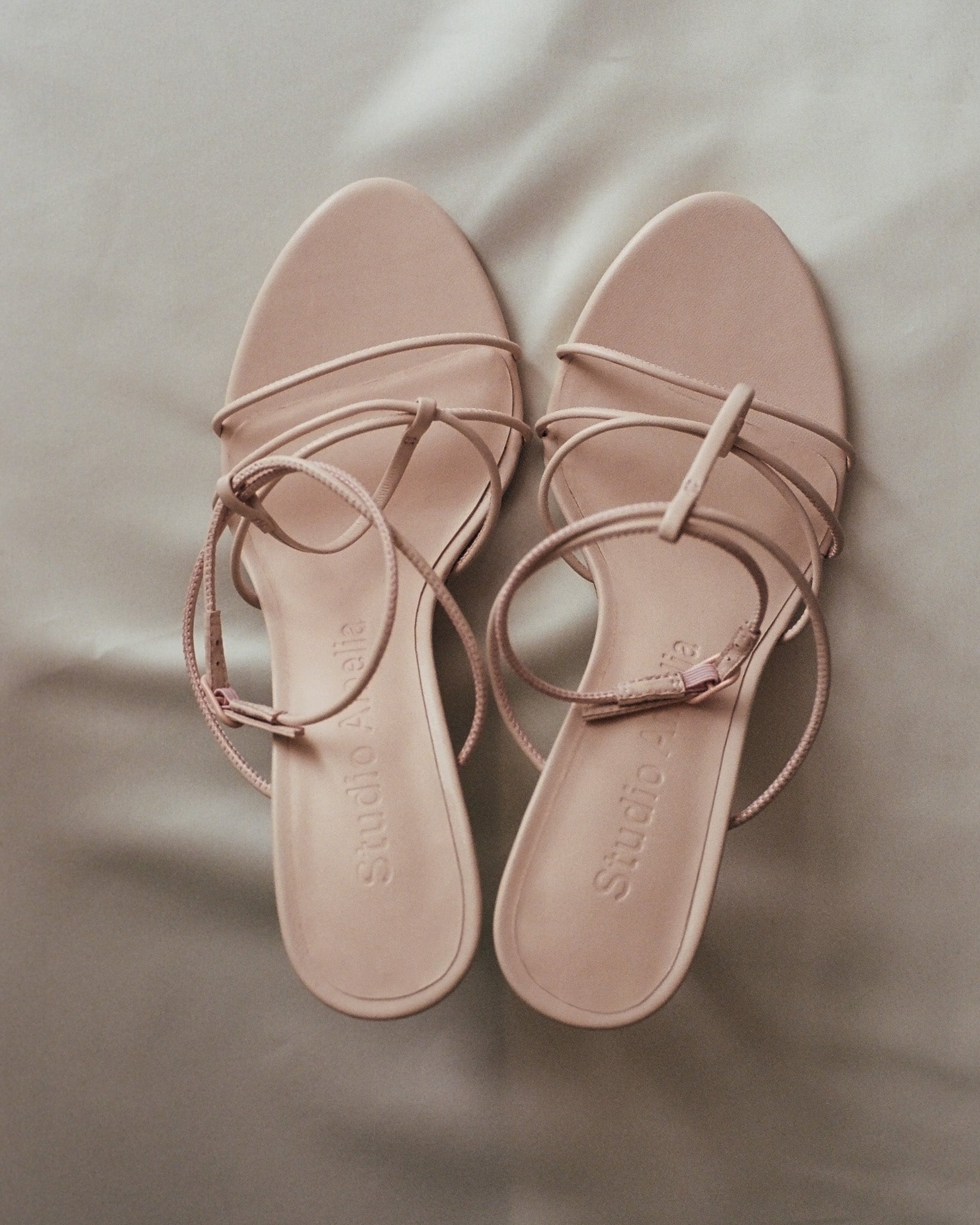 A pair of blush pink leather sandals with thin straps
