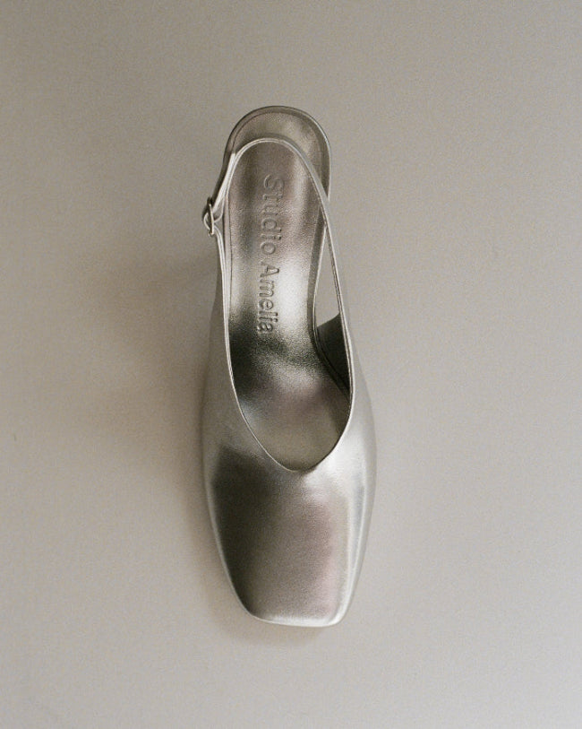 Silver high-heeled shoe on a light gray background