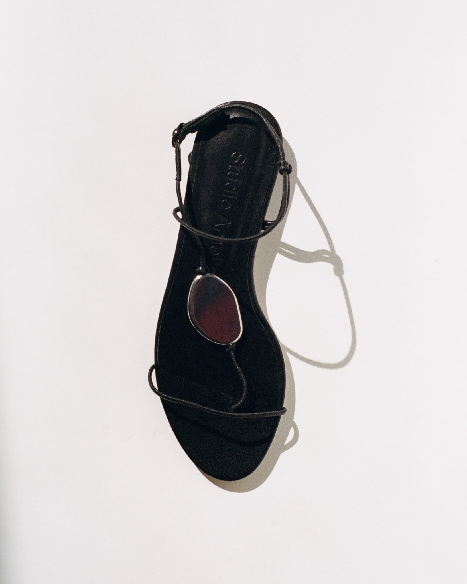 Black sandal with thin straps on a white background