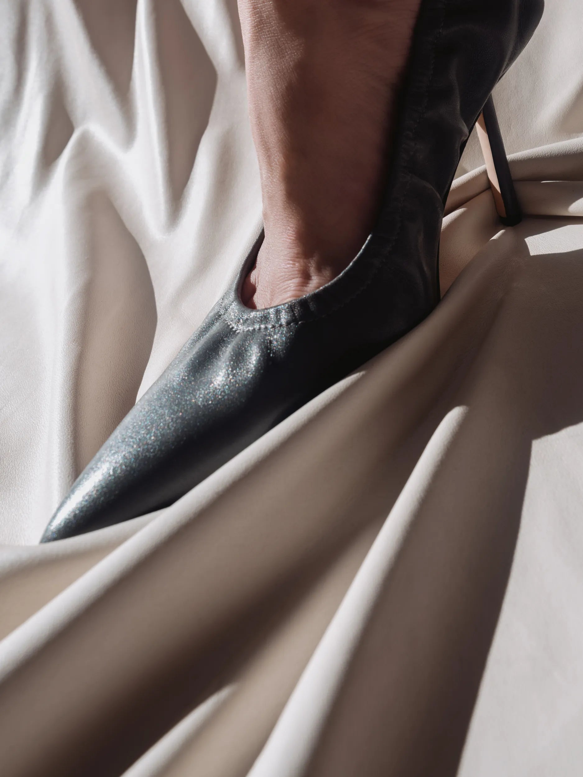 A woman wearing a grey pointed leather pump with a high heel