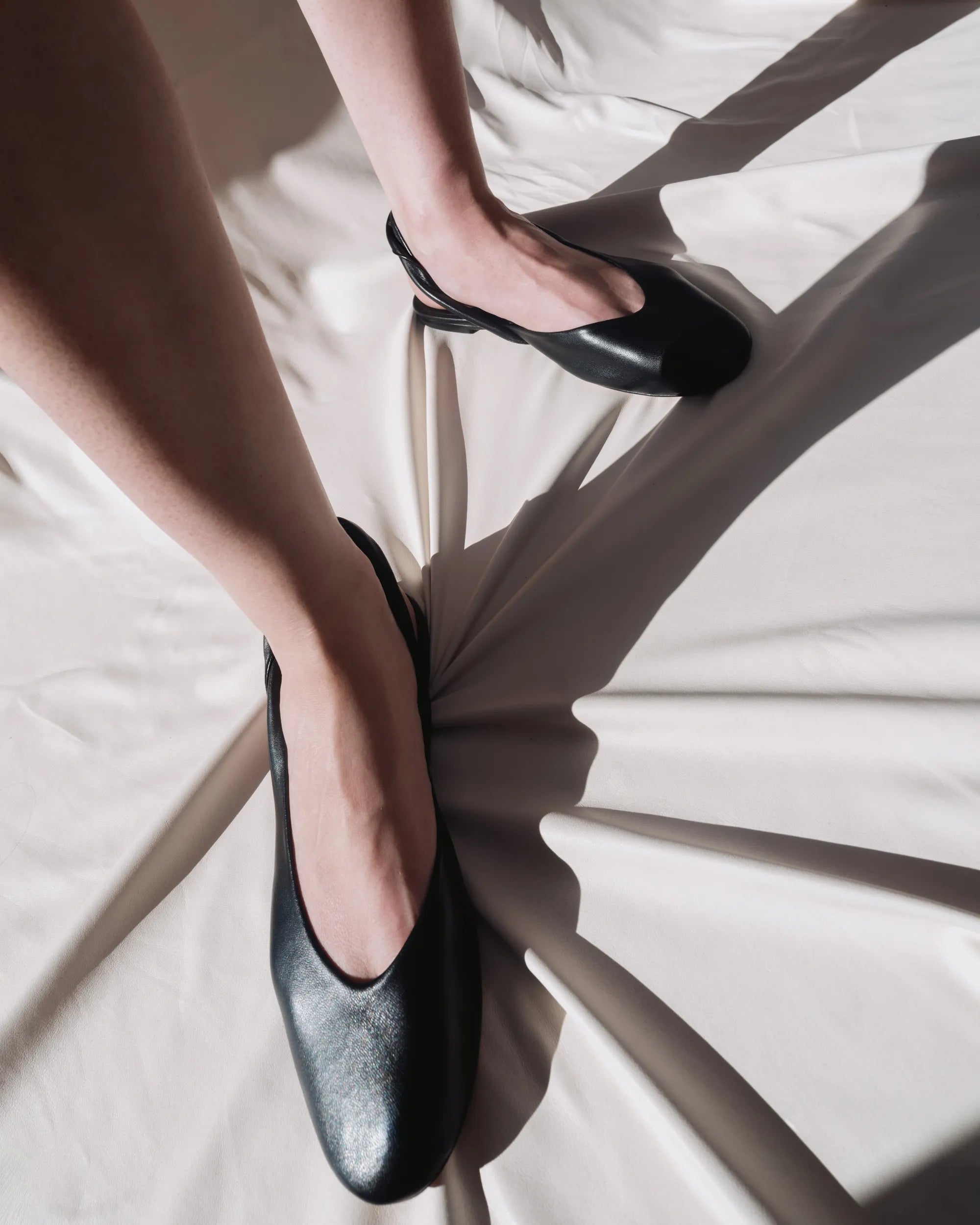 A person wearing black ballet flats made from leather