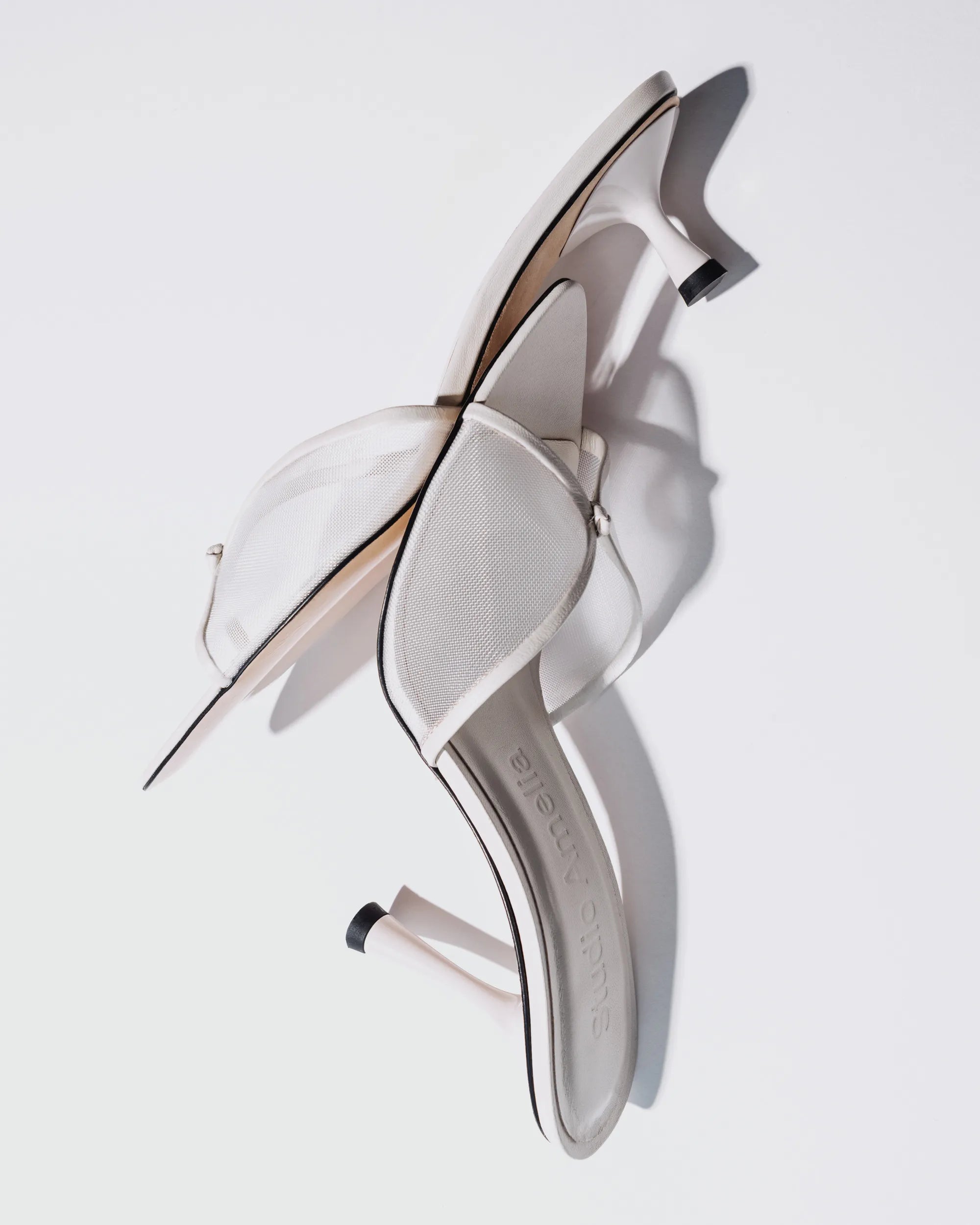A pair of white leather kitten heels with mesh upper