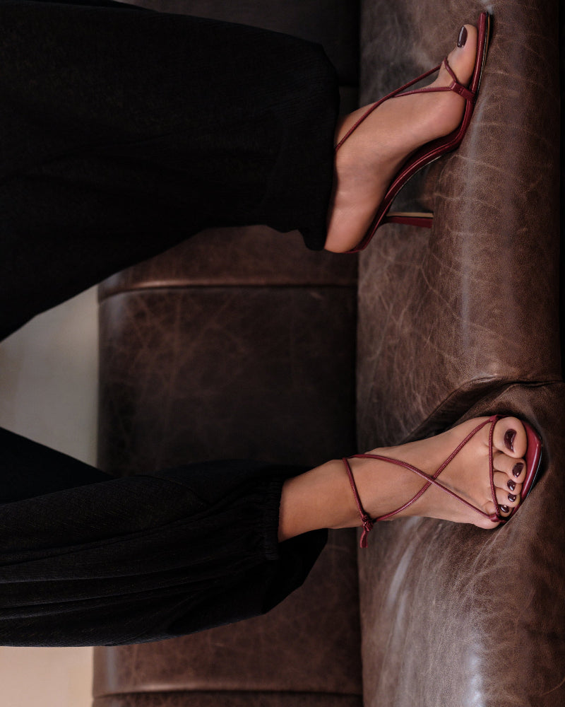 A person wearing red strappy sandals with mid heel