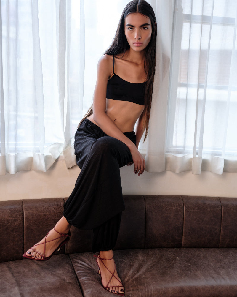 A woman sitting on a couch wearing red strappy sandals