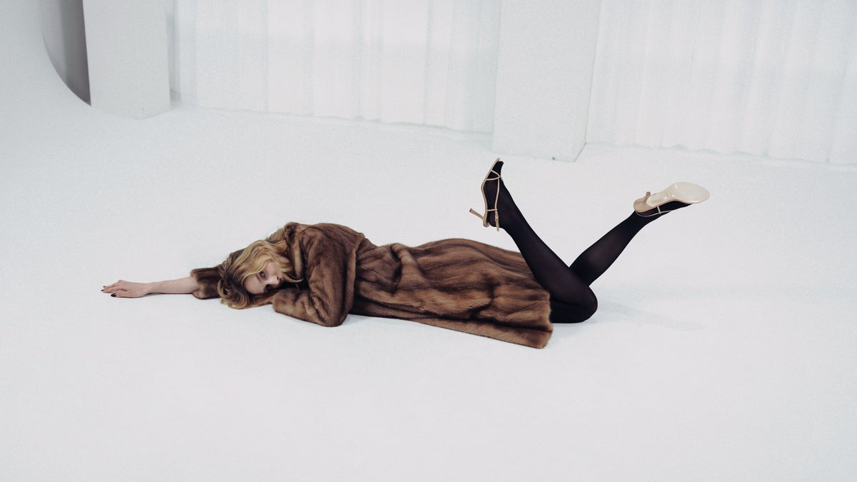 A woman wearing beige leather open-toe sandals by Studio Amelia