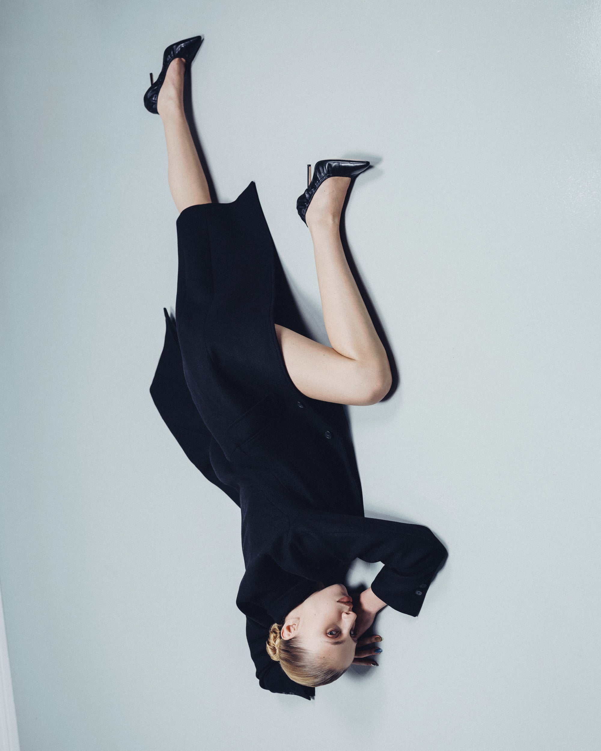 A woman lying on the floor wearing black leather pointed pumps