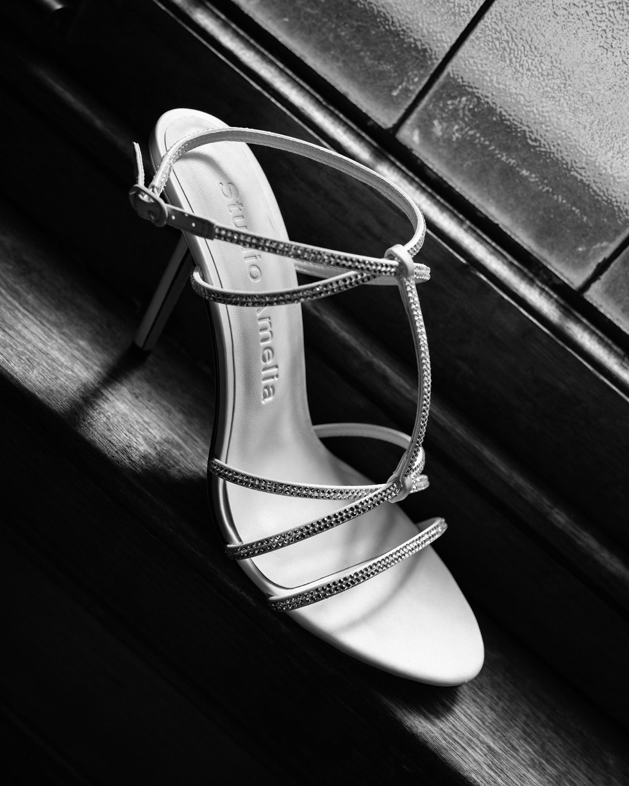 High-heeled shoe with thin straps on a dark background