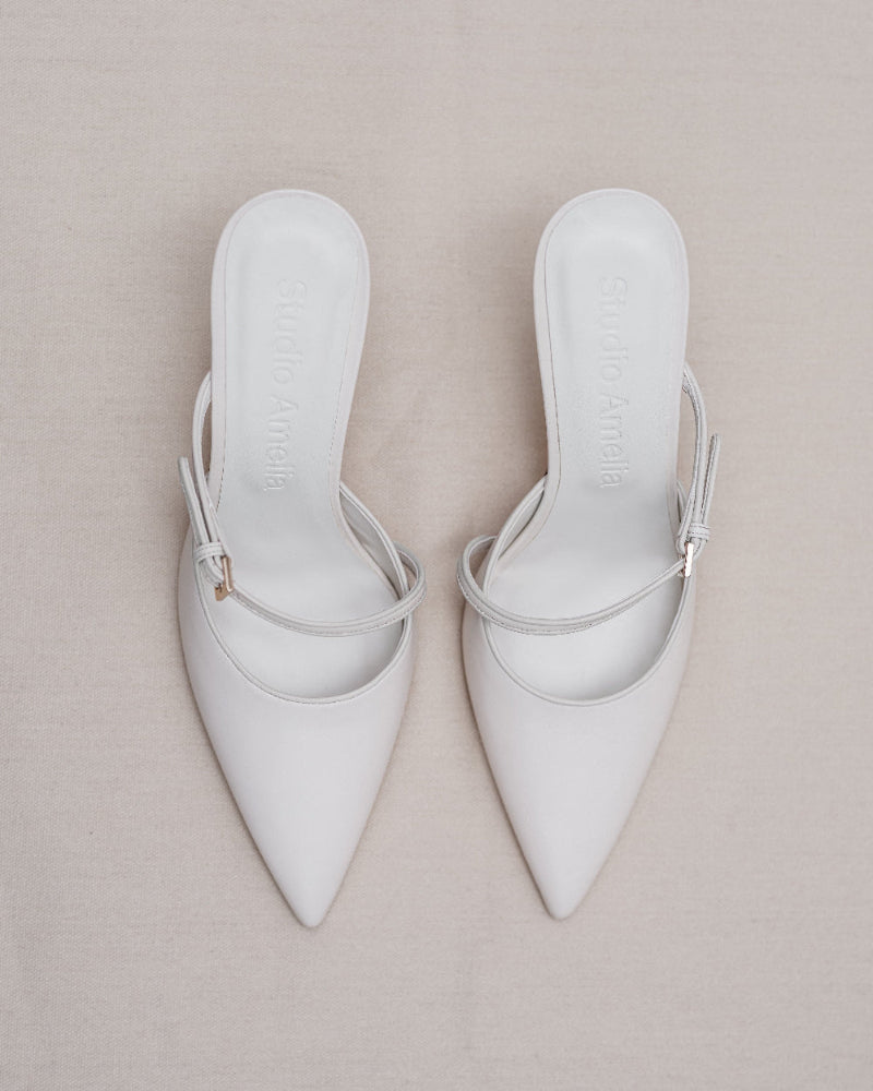 A pair of cream coloured pointed high heels with buckle