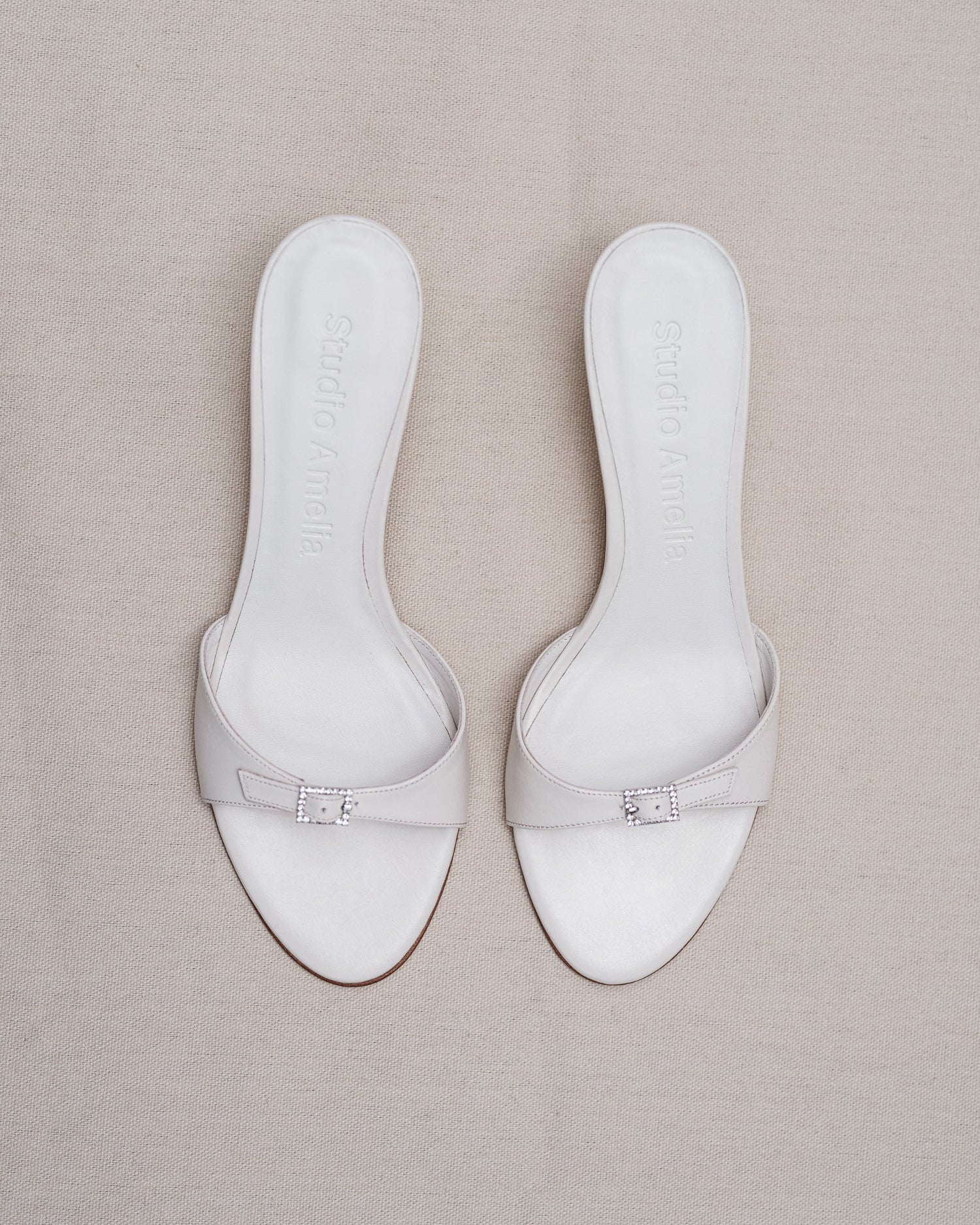Pair of white sandals on a beige surface