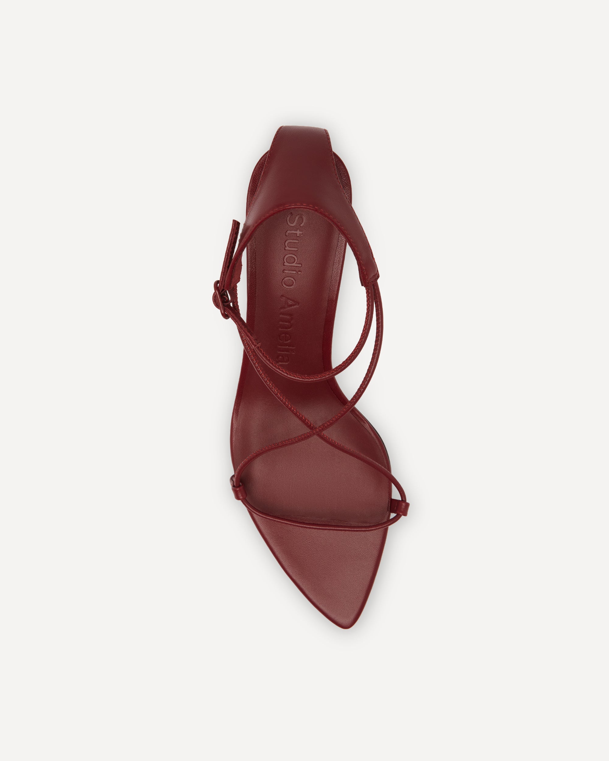 Maroon high-heeled shoe with strappy design on a white background