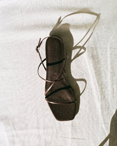 Brown sandal with thin straps on a white fabric background